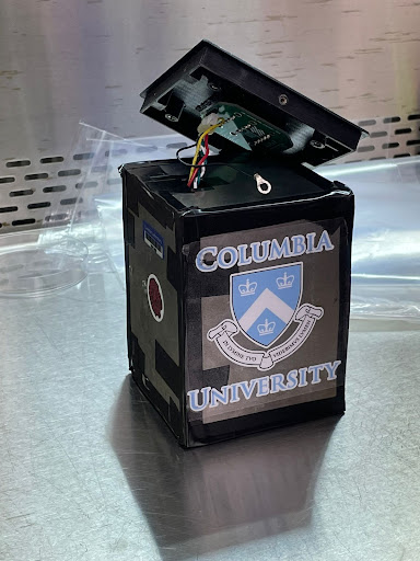 A black cube with a Columbia University sticker on the side is propped open to reveal some wiring inside